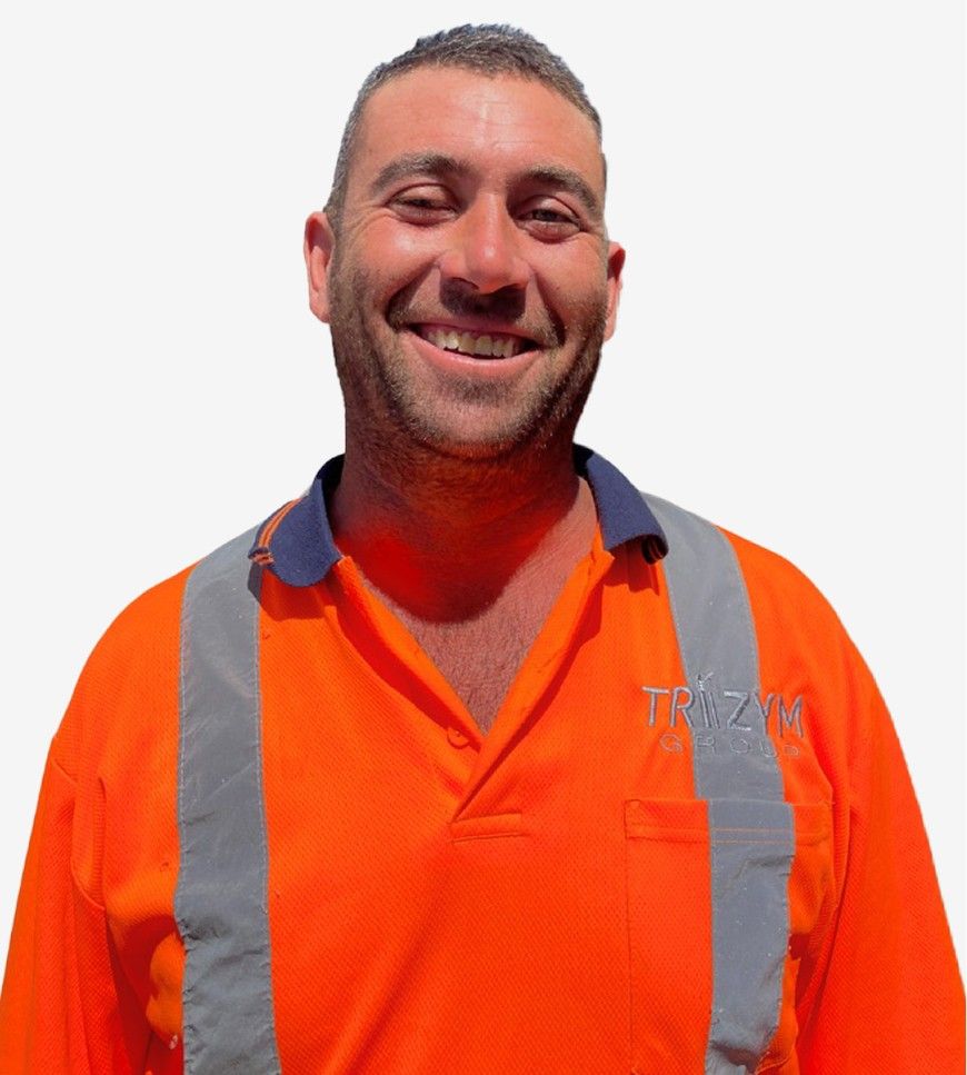 A person wearing an orange high-visibility shirt with reflective strips and an embroidered logo stands smiling against a white background.